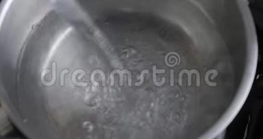 不锈钢厨房锅充满清洁水从水龙头。 从锅内的水龙头流出的水。 泼水